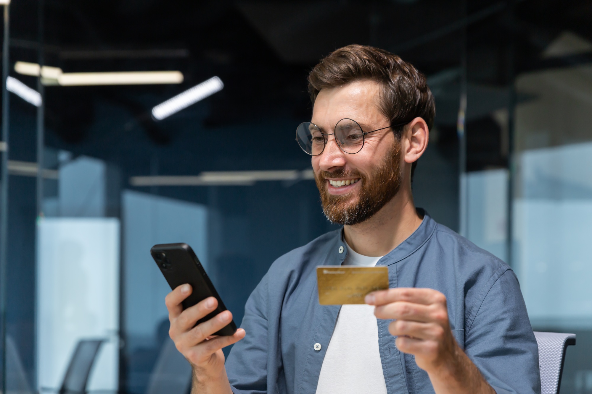 Cheerful and smiling bearded businessman doing online shopping and bank money transfer, freelancer